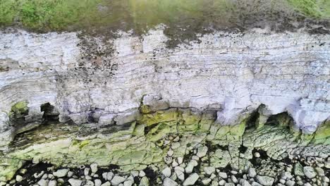 Beautiful-chalk-coastal-cliffs-at-low-tide,-with-visible-cracks-showing-in-the-cliff-faces