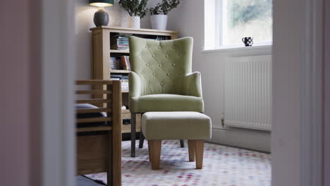 interior of a room with an armchair, footstool, and bookshelf