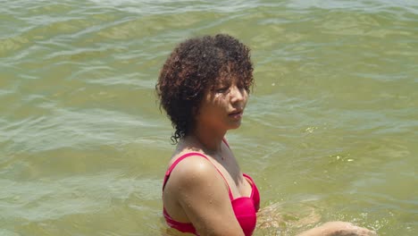 Enjoying-a-tropical-beach,-a-Latina-beauty-with-curly-hair-showcases-her-allure-in-a-sexy-bikini