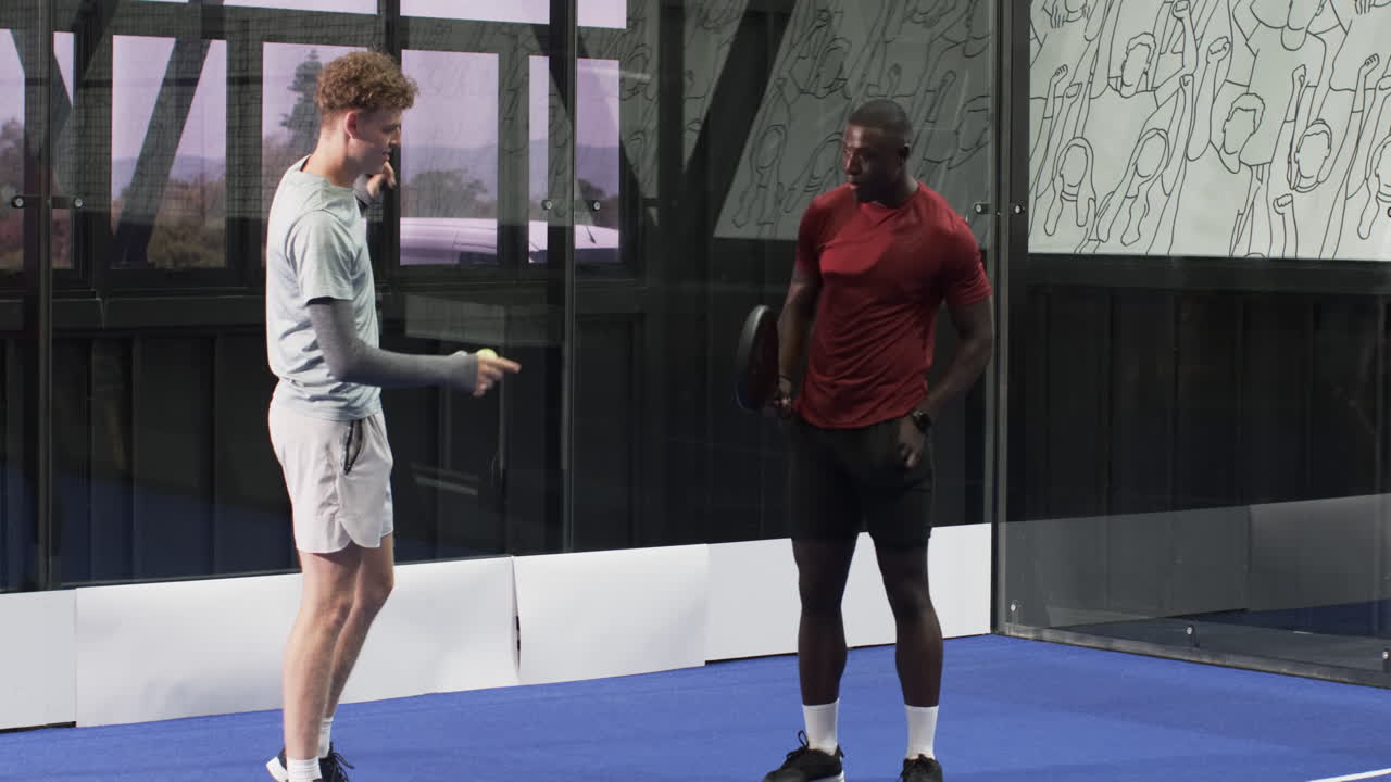 Two diverse men playing padel tennis indoors, focusing on competitive game action, at indoor court