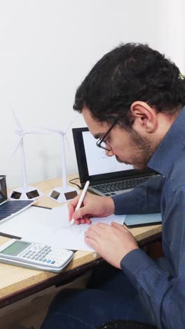 engineer drawing a blueprint at his desk, side view