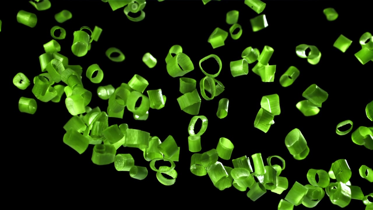 Chopped Green Onions Falling in Slow Motion on Black Background