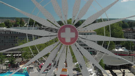 beautiful aerial drone crane shot flying backwards of amusement park ferris wheel and free fall tower with the city and lake of zürich, switzerland in the background during zürichfest