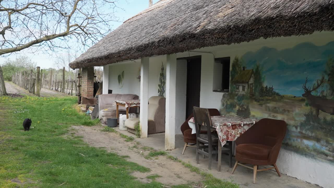 Exterior of a rural house with mismatched furniture and painted wall mural