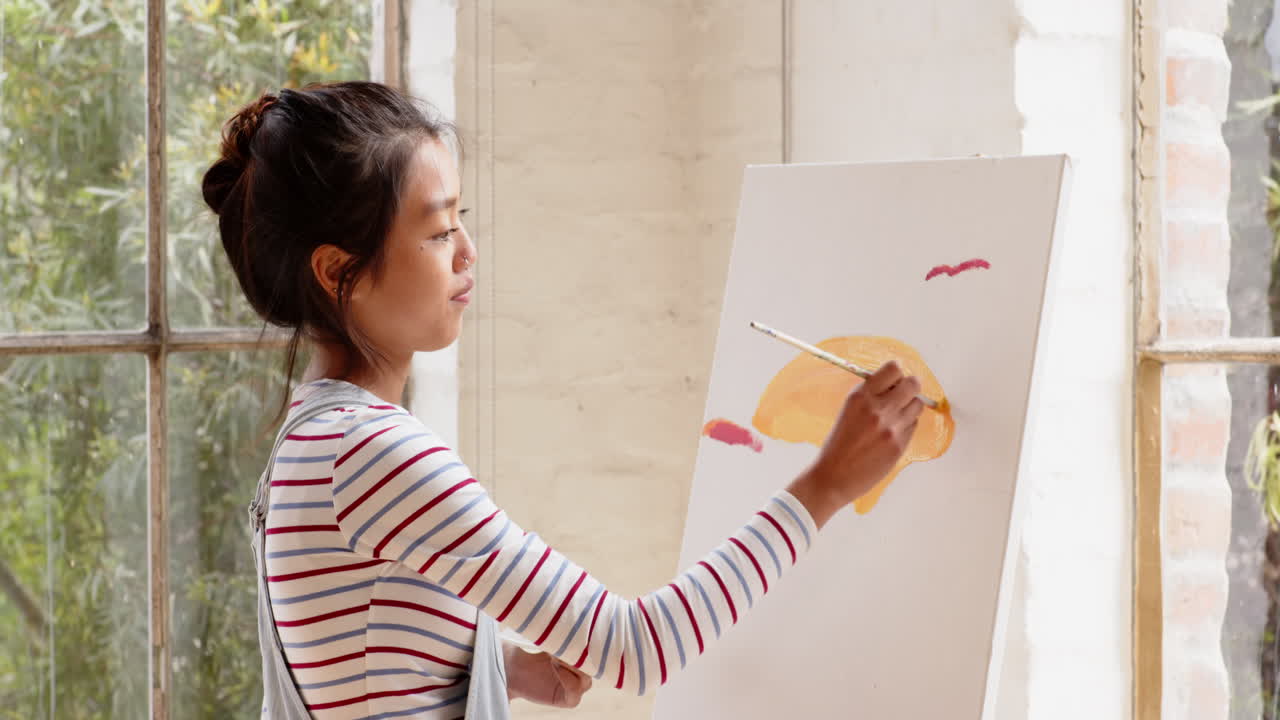 Asian young woman painting on canvas at home with smiling woman, enjoying creative time