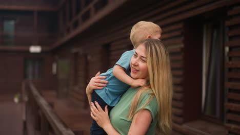 Blonde-Frau-Umarmt-Kleinen-Jungen-Auf-Der-Terrasse-Eines-Hotelgebäudes