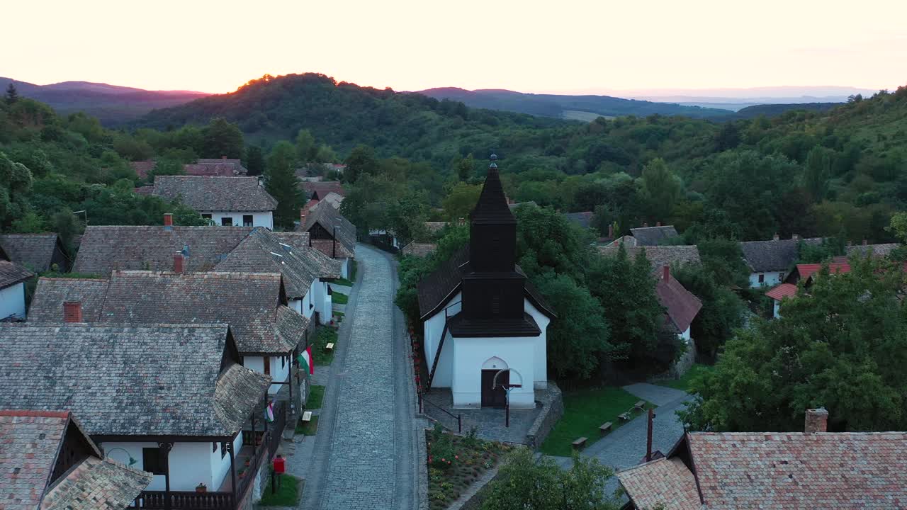 Drone flies over the historical streets of Holloko, Hungary in the sunset. Drone flies slowly right