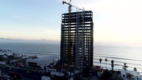 Drone-Volando-Alrededor-De-Un-Edificio-En-Construcción-Frente-A-La-Costa-Del-Mar