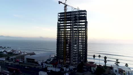 drone volando alrededor de un edificio en construcción frente a la costa del mar