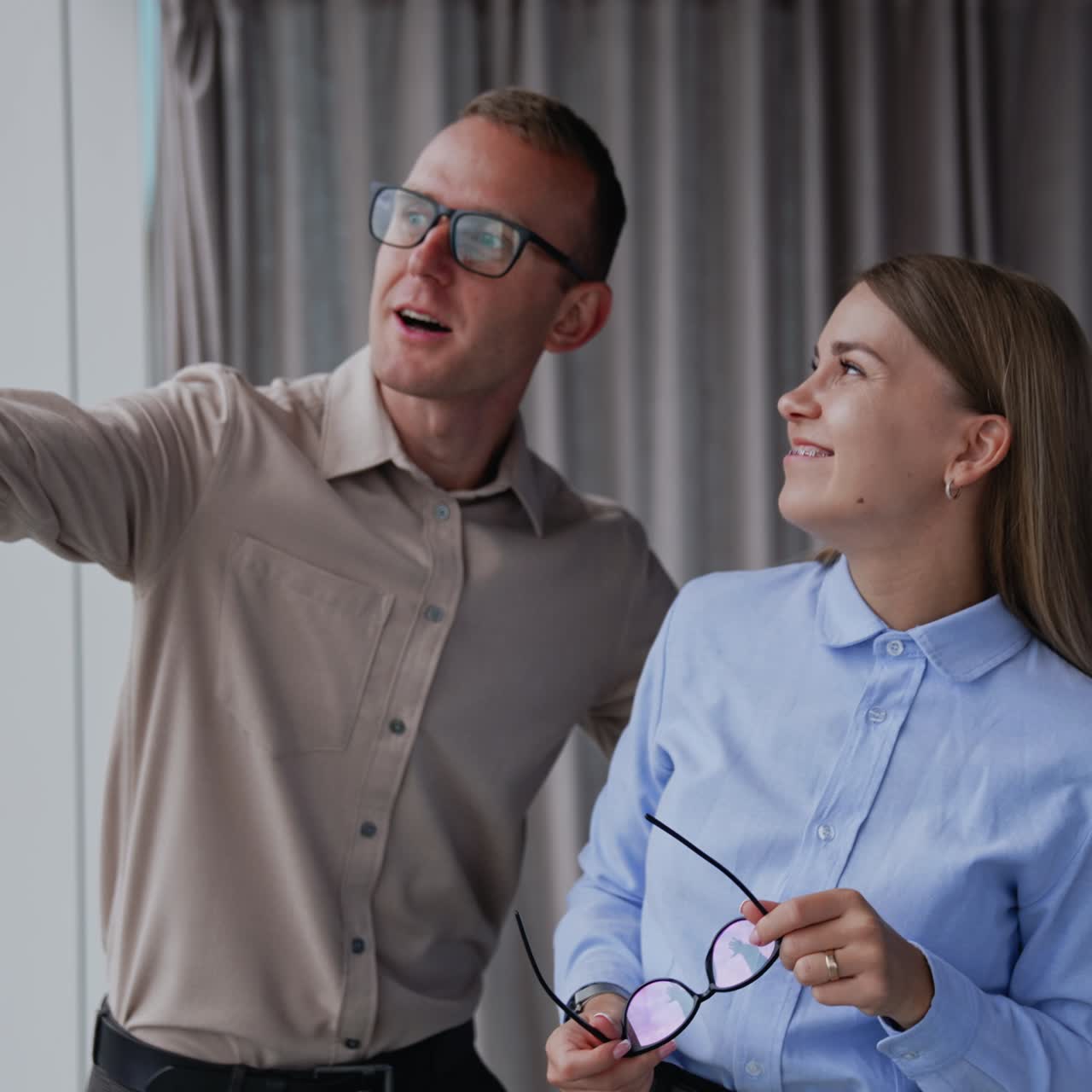 Young lady having headache and feels tired. Male colleague tries to comfort her and distract her pointing at window