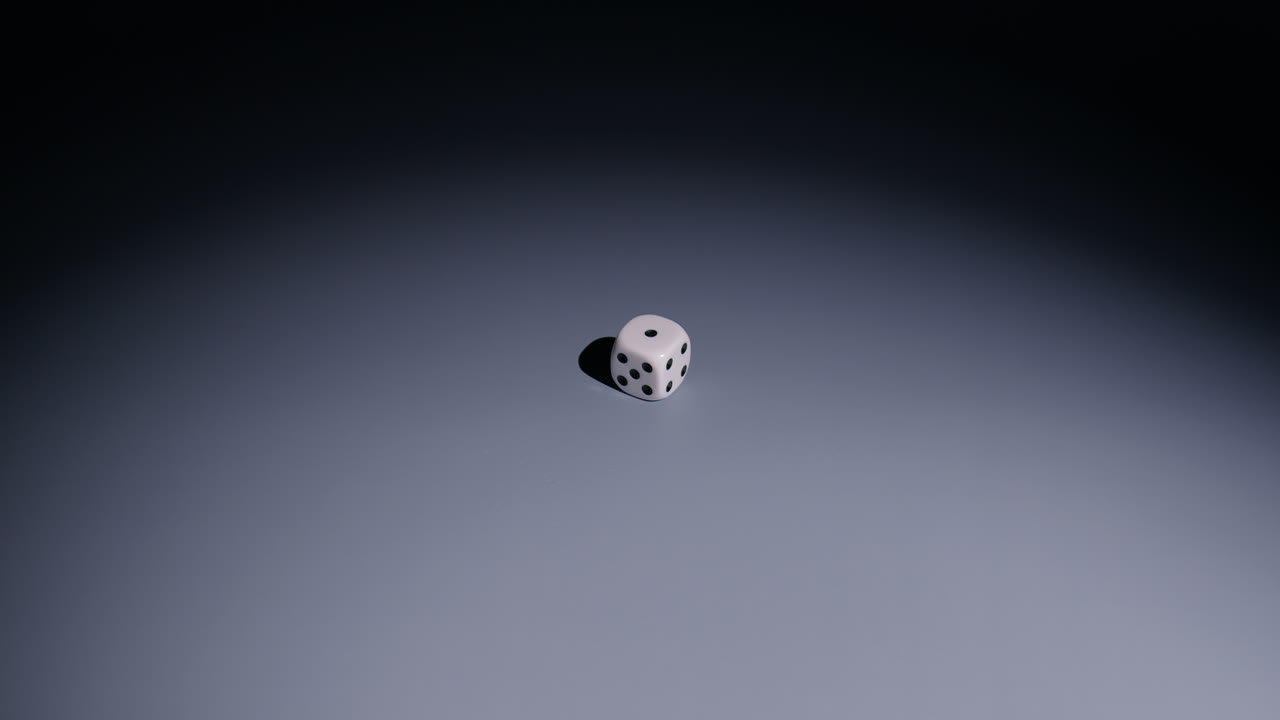 Slow-motion wide-shot of a white die being showered by a large amount of tiny dice