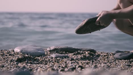 beautiful woman in bikini lays stones on the beach in a balanced way