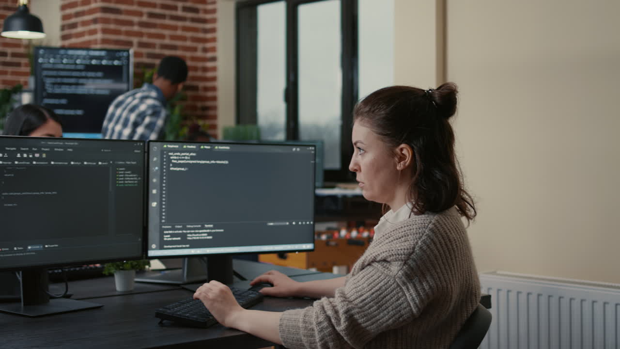 Portrait of focused software engineer writing code looking at multiple computer screens