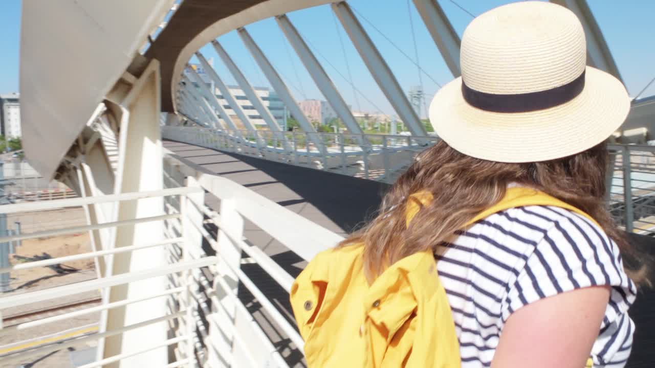 The traveler crosses a pedestrian bridge in the terminal, heading toward her gate.