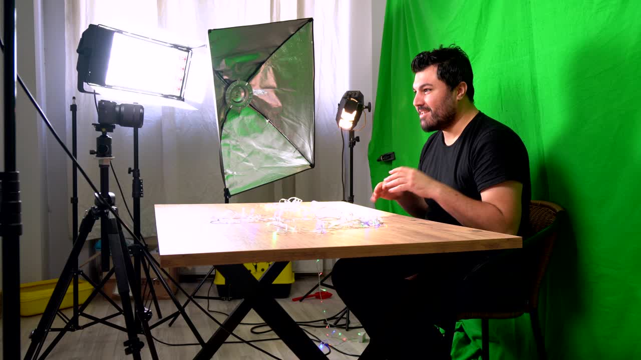 Uomo vlogger che registra un video per YouTube nel suo studio domestico con schermo verde e telecamera