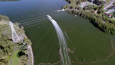 dynamic aerial perspective: speedboat cutting through tranquil waters near a lush riverbank