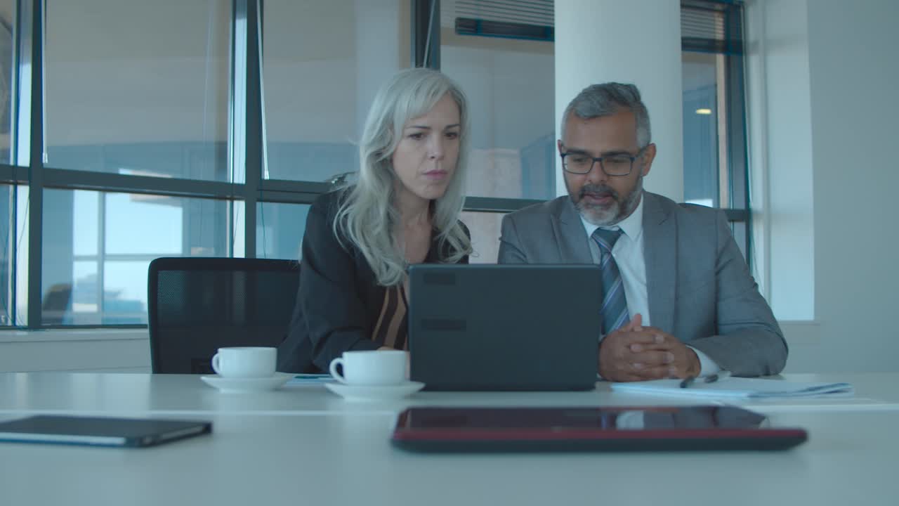 colleghi d'affari seri che guardano contenuti sul portatile