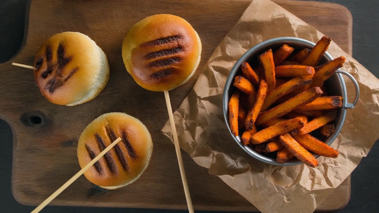 Pães de Slider Grelhados e Batatas Fritas de Batata-Doce em uma Tábua de Madeira