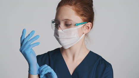 redheaded doctor in front of camera on gray background.