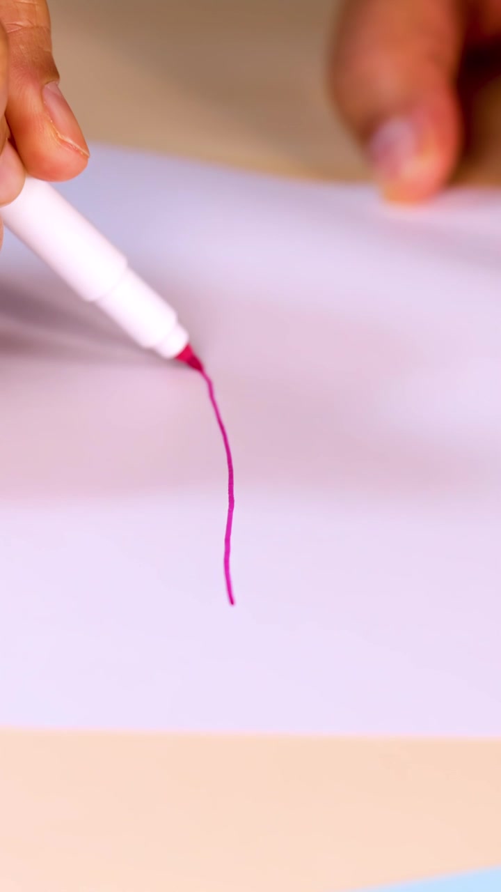 Detail ruky kreslící červenou čáru fixem na bílý papír, jasné osvětlení.
