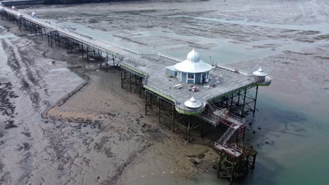 Bangor-seaside-pier-North-Wales-silver-spire-pavilion-low-tide-aerial-view-wide-orbit-right