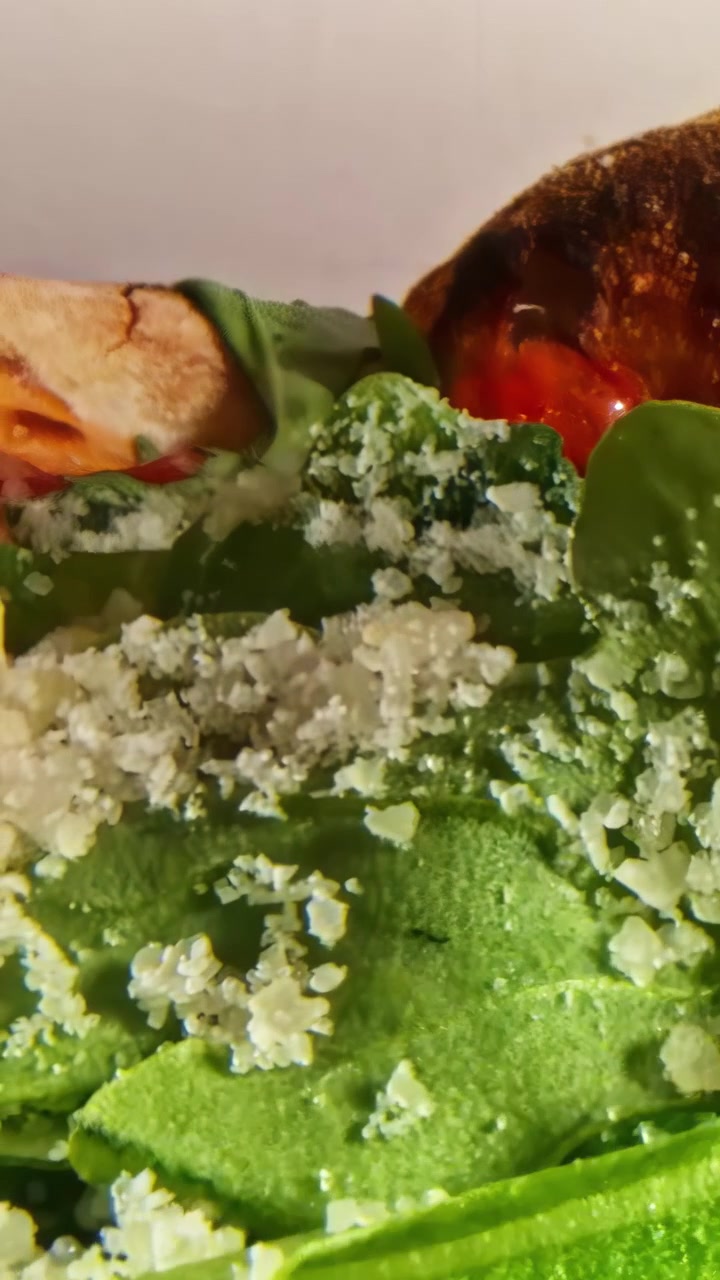 Primo piano macro di una deliziosa insalata verde con parmigiano, crostini e condimento che ruota