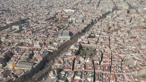 Aerial-panoramic-footage-of-streets-and-buildings-in-city-centre,-landmarks-along-wide-La-Rambla-boulevard.-Barcelona,-Spain