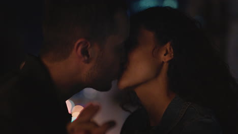 young caucasian couple kissing on rooftop at night enjoying romantic relationship in peaceful urban city evening