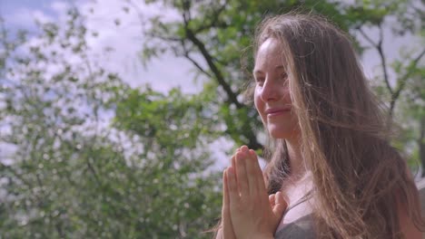 retrato de una joven caucásica en pose de oración meditando al aire libre, día