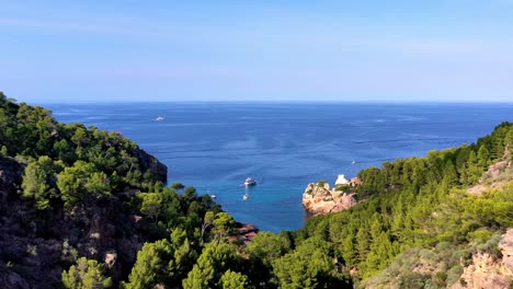 Cala-Deia-En-Mallorca-España-Con-Yate-Blanco-Estacionado-Junto-A-La-Cala,-Pedestal-Aéreo-Levantado