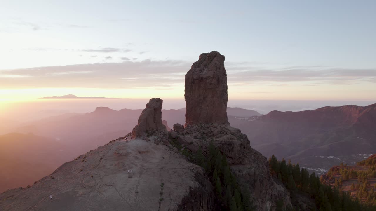 Circular drone flight around Roque Nublo with an orange glow of the sunset in Gran Canaria.