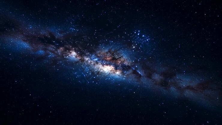 Vista panoramica distante della Via Lattea che si estende attraverso un cielo notturno indaco profondo, con un nucleo luminoso e cremoso, sottile foschia ambrata, corsie di polvere scure, stelle sparse e profonda quiete cosmica, con galassia