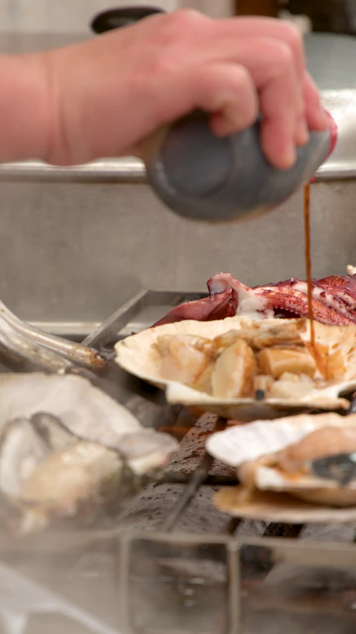 Close-up shot of a vendor pouring sauce onto fresh scallops grilling at a market