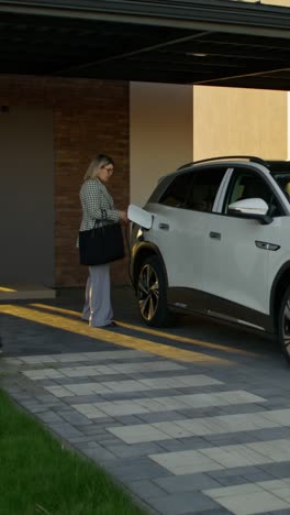 mujer cargando un coche eléctrico en casa