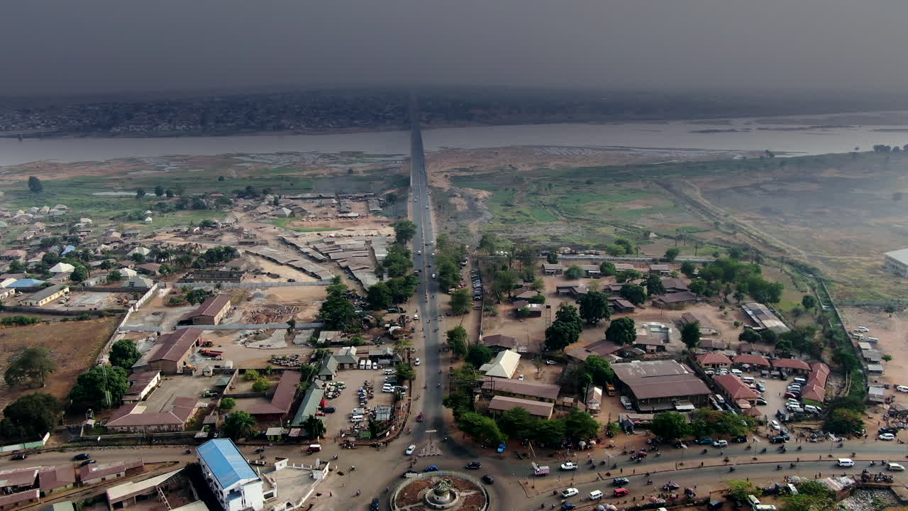 Rodovia, rotatória e ponte com o Rio Benue e cidade densamente povoada no horizonte, na Nigéria, África Ocidental - vista aérea