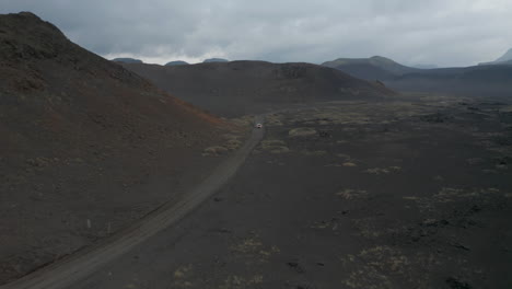 High-angle-view-car-driving-peacefully-through-desert-remote-dust-road-in-icelandic-highlands.-Drone-view-4x4-suv-vehicle-discovering-wilderness-iceland-countryside.-Adventure-and-exploration