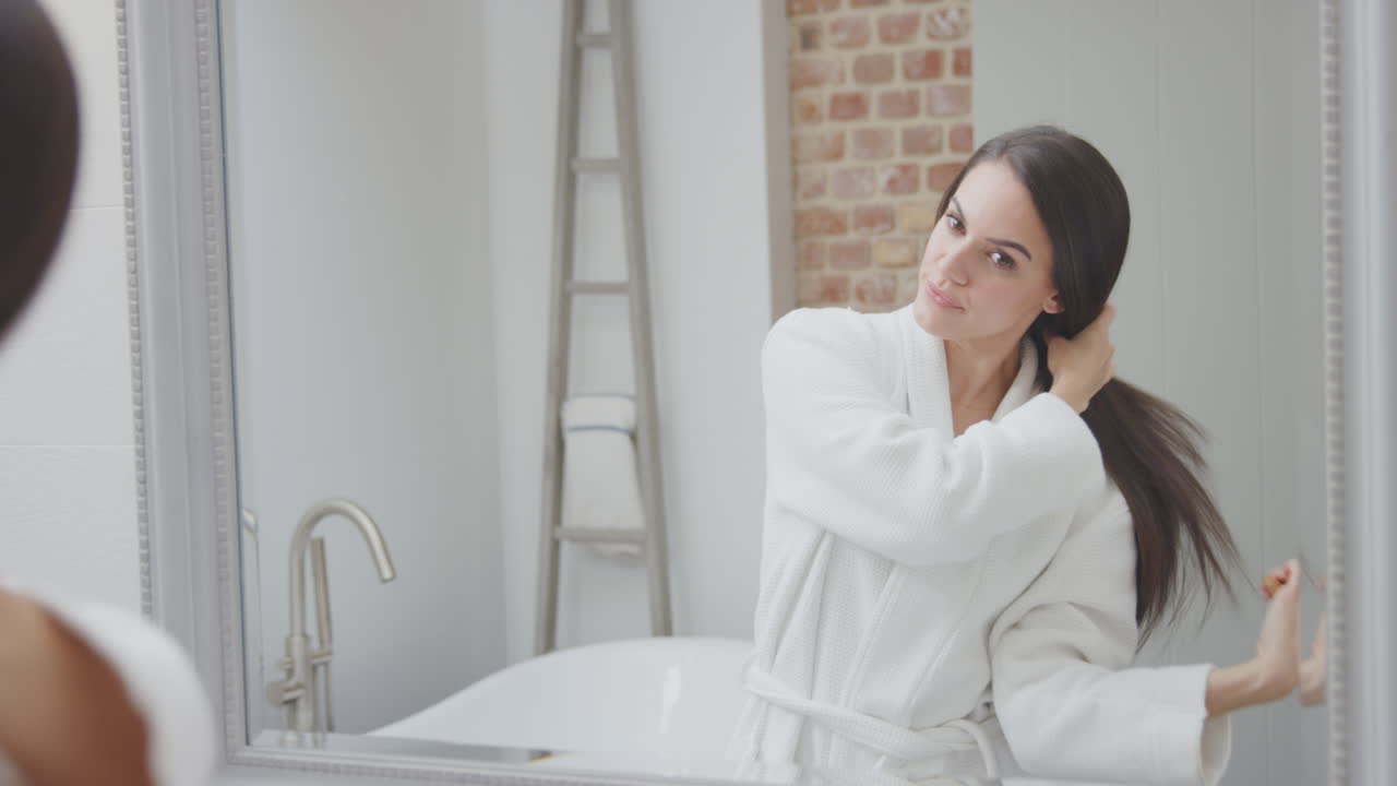 목욕복과 피자마를 입은 부부는 집에서 목욕실 거울에 준비하고 있습니다.