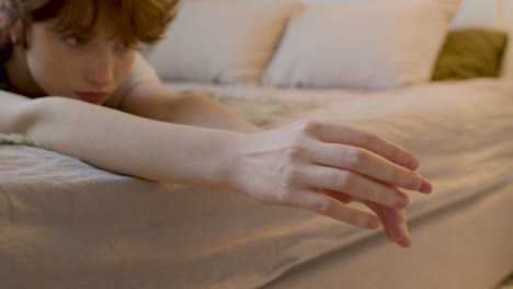 thoughtful girl lying on the bed with outstretched arms