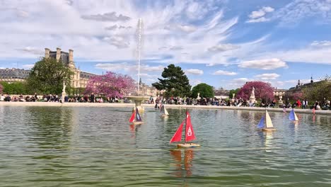 toy sailboats floating in parisian garden fountain