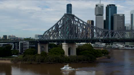 one of the few boats allowed to travel up the very brown brisbane river after the floods in february 2022 , is seen going under the iconic story bridge