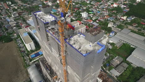 Aerial-view-of-modern-high-rise-building-under-construction-in-the-busy-city-centre-business-district-with-workers,-scaffolding-and-crane