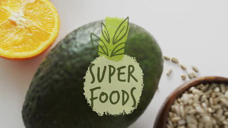 animación de texto de super alimentos sobre aguacate, rebanada de naranja y semillas sobre fondo blanco