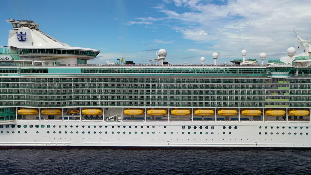 Side angle drone shot of cruise ship showing suites and life boats docked in the Cayman Islands