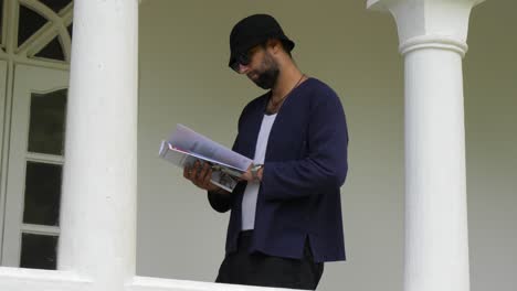 man reading magazine on a porch