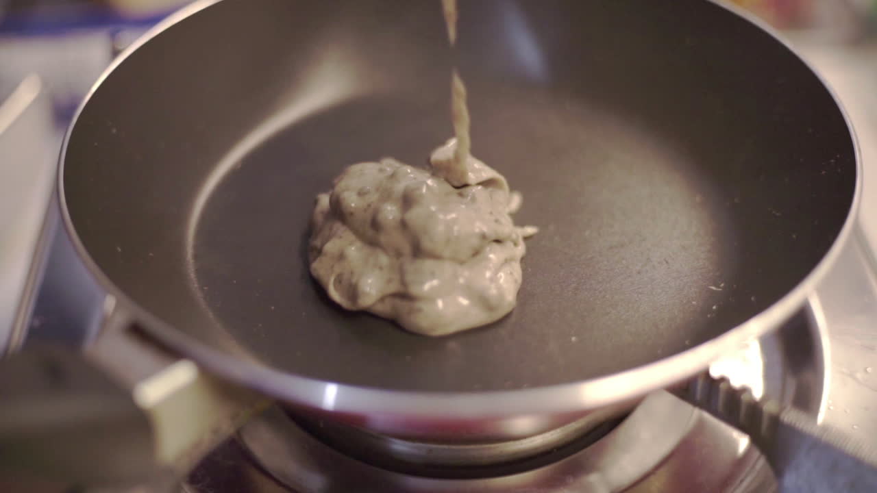 Pouring Oreo Pancake Batter Mixture To Teflon Pan Over The Stove - Closeup Shot