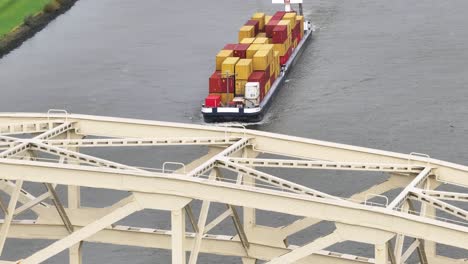 aerial reveal of cargo vessel with goods sailing along wide river water