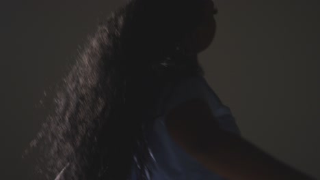 backlit studio shot of young woman dancer dancing against grey background