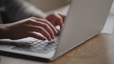 close-up young woman typing on the keyboard of a laptop sitting at home. remote work from home. home office