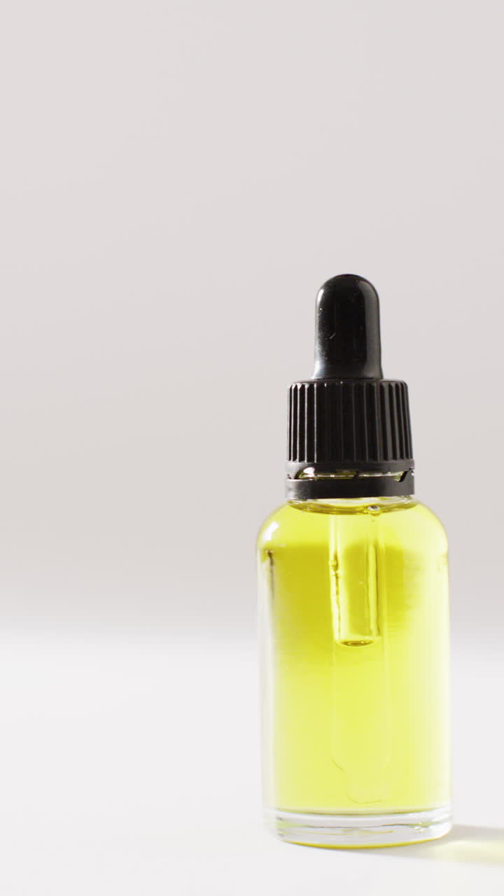 Vertical video of dropper serum bottle on white background with copy space
