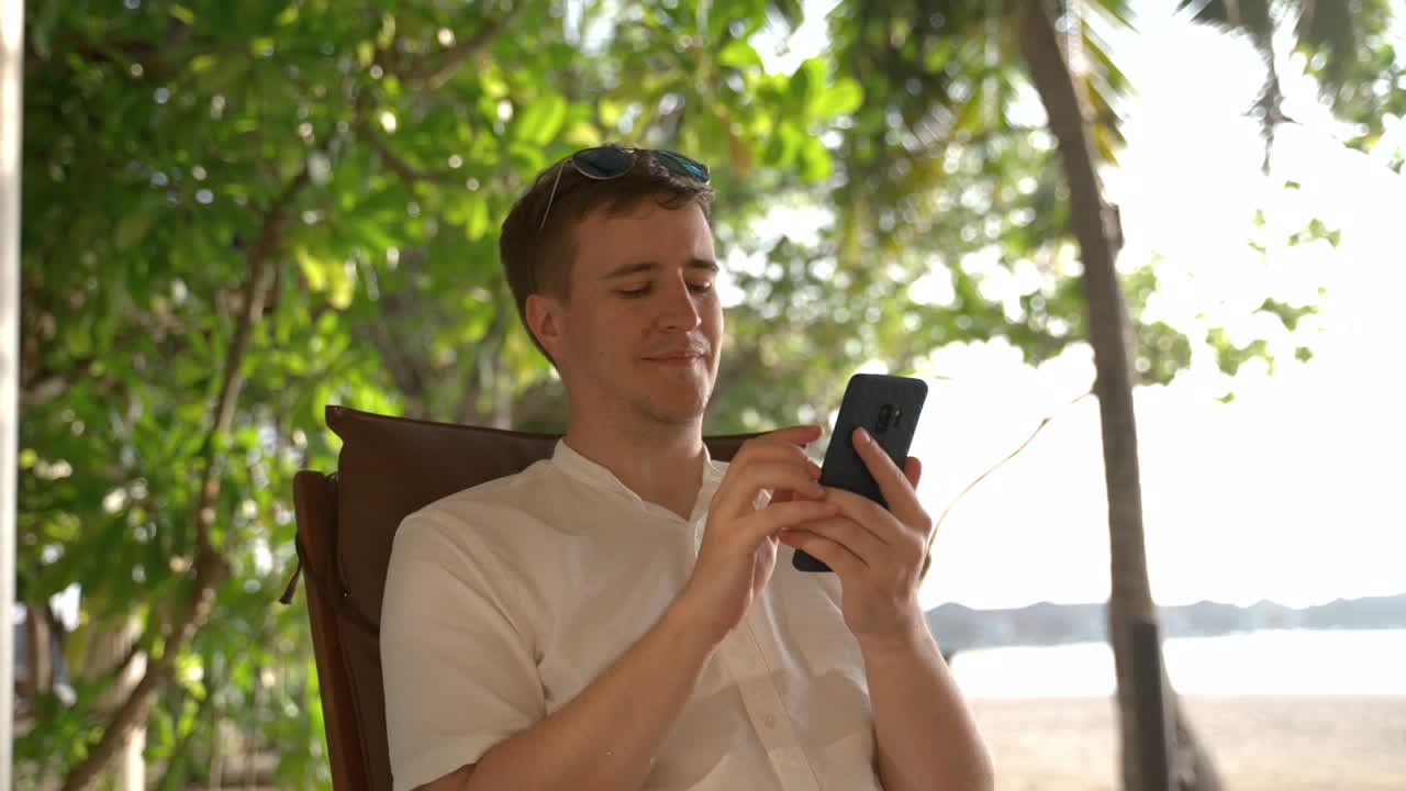 열대 섬 에서 전화 로 정보 를 찾고 있는 젊은 남자